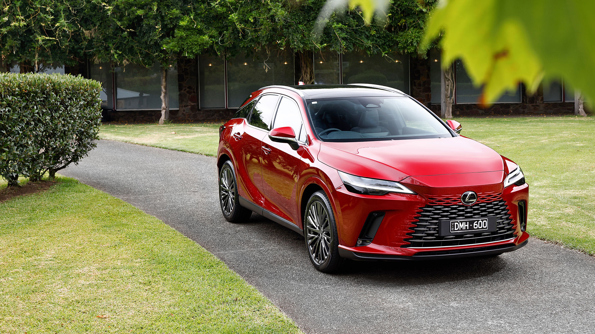 Lexus RX 450h+ parked on a driveway in front of a lawn