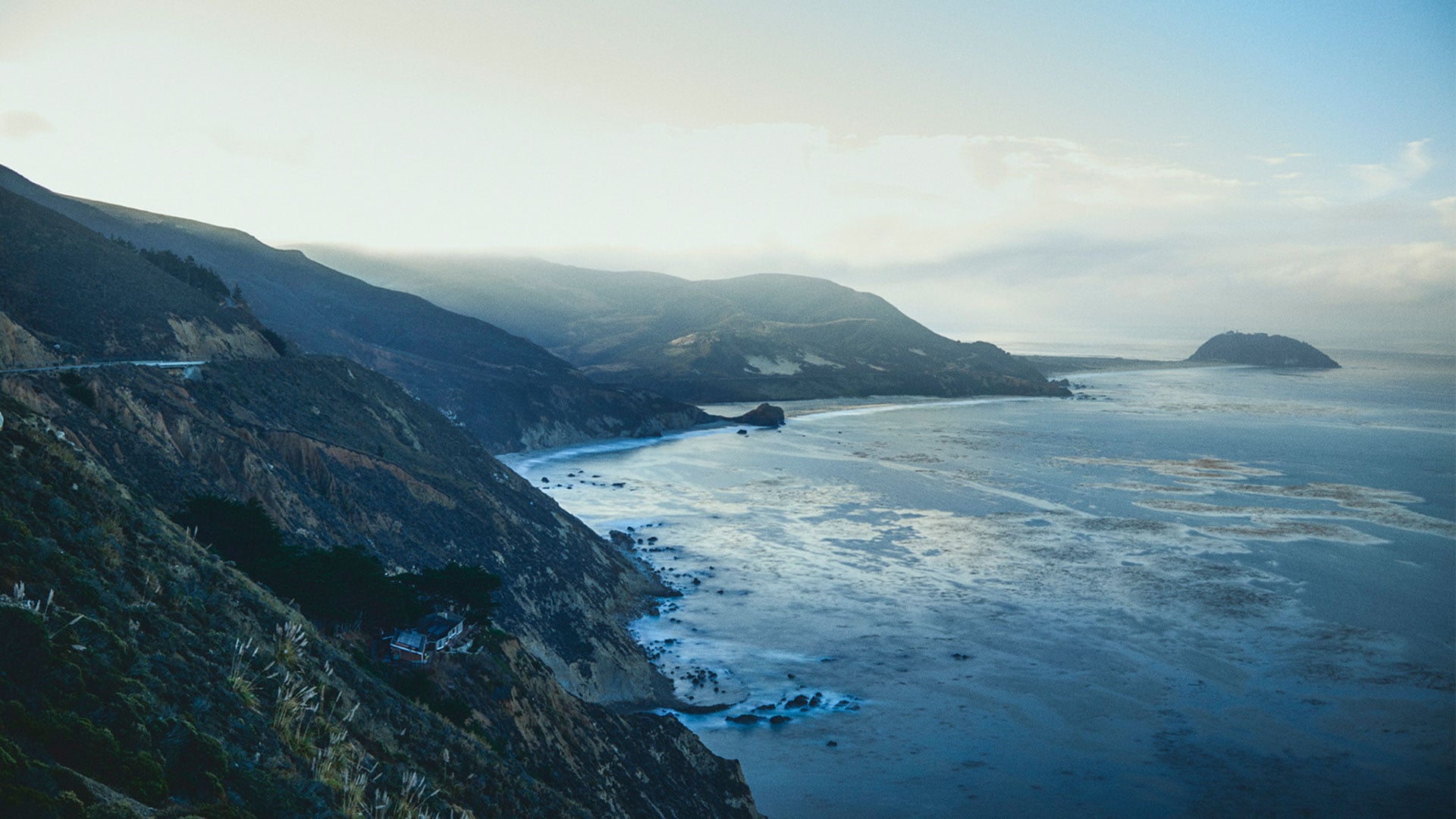 Tall mountains loom against the sea