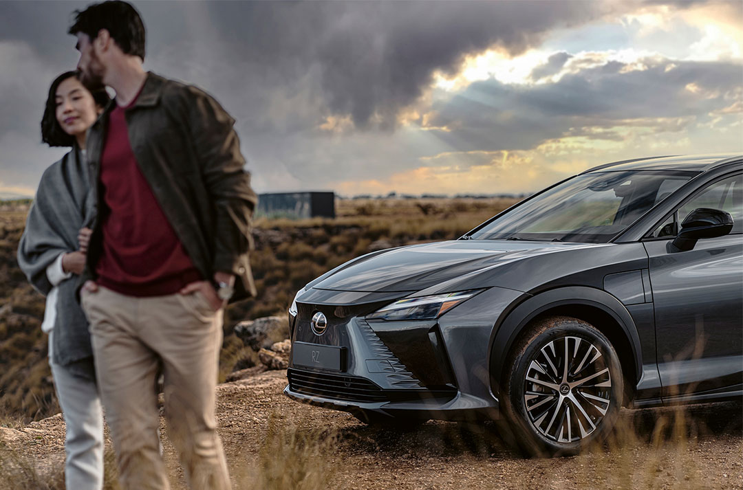 A couple walk away from a parked Lexus RZ