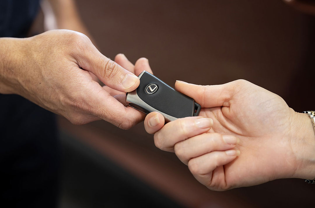 Two hands exchanging Lexus car keys