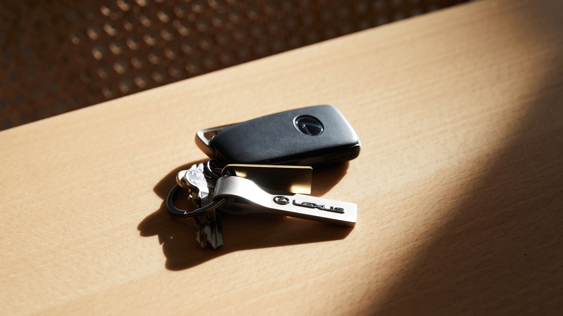 Set of Lexus keys on a table. Sunlight streams onto them.