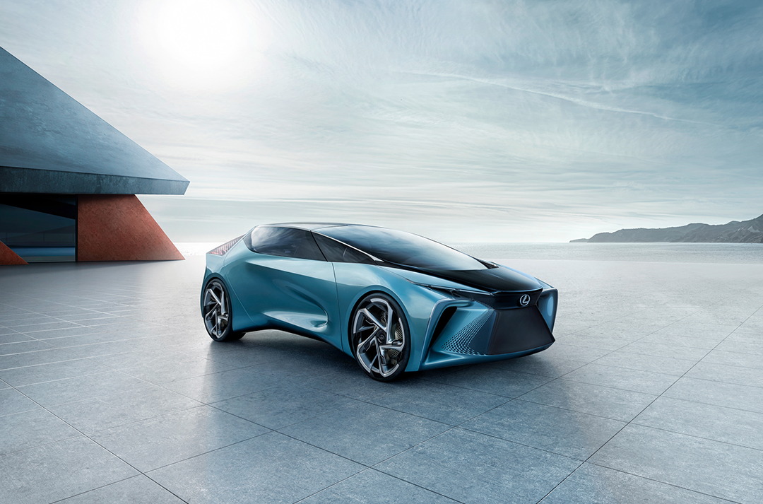 A metallic blue LF-30 Electrified concept car parked on a paved ground with sky and seascape in background